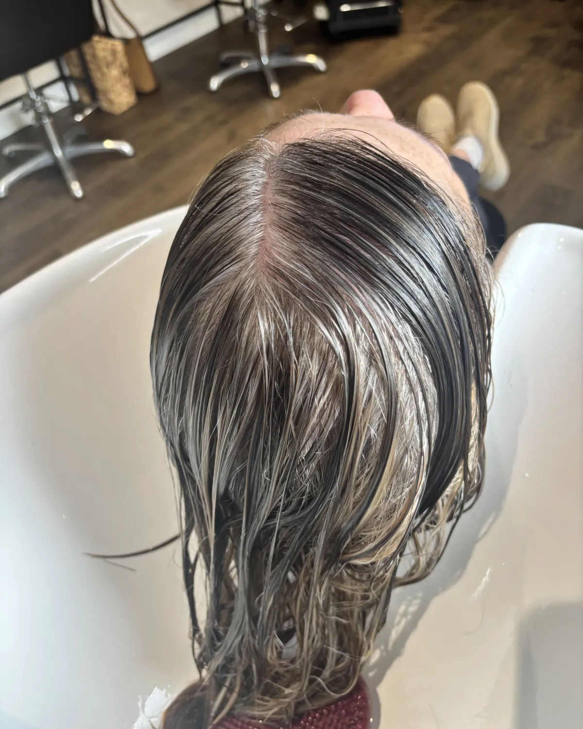 Mid-process grey blending — soft root placement at MNR Hair wash basin